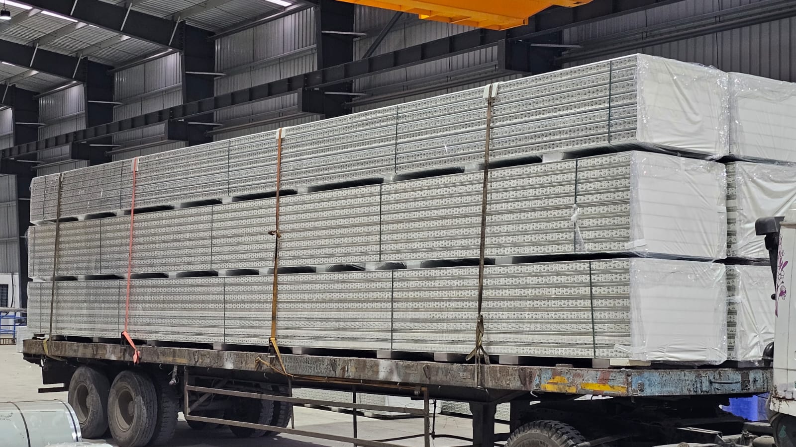 Wrapped bundles of insulated panels loaded on a transport truck inside factory loading bay