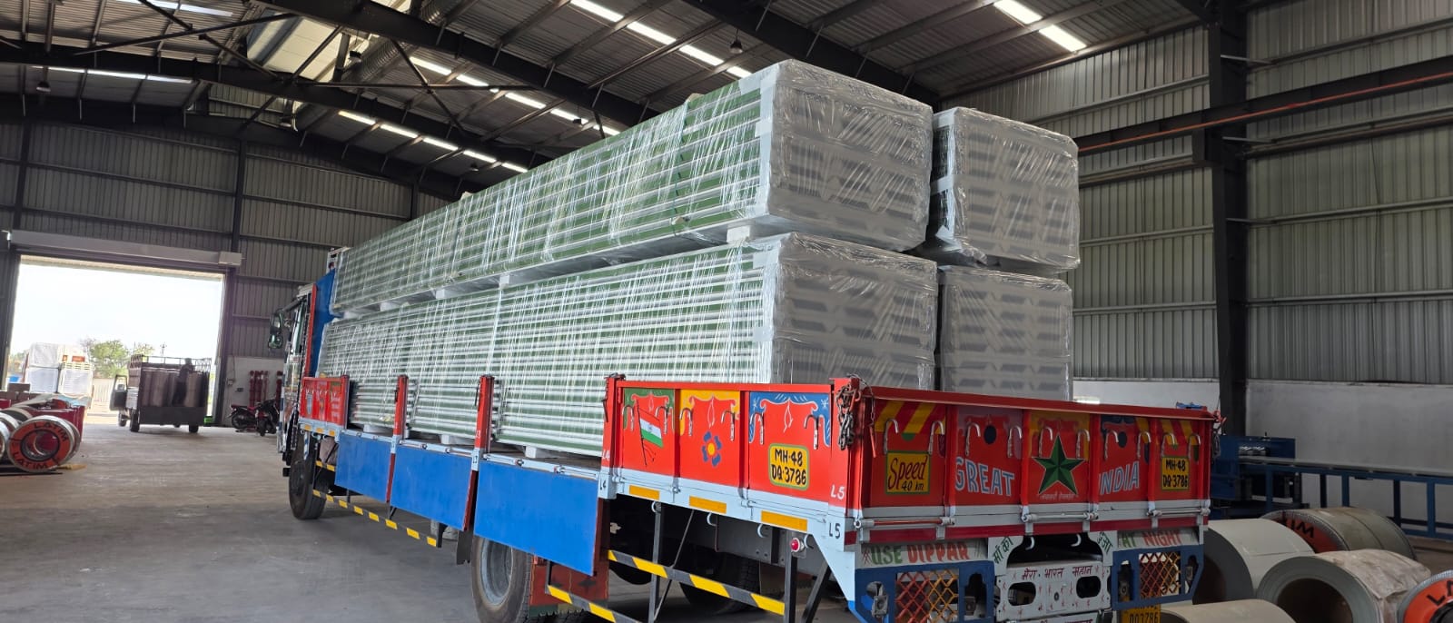 Colorful transport truck loaded with green-tinted PUF panel bundles inside factory